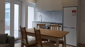 Eine moderne Küche mit weißen Schränken, einem Holztisch und Stühlen.