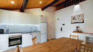 Eine moderne Küche mit weißen Schränken, einem Holztisch und einer Mikrowelle.