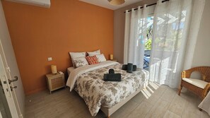 Ein Schlafzimmer mit Bett, Nachttisch, Stuhl und Blick ins Freie.