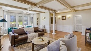 Un salon spacieux avec un haut plafond, de grandes fenêtres et une cheminée.