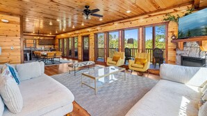 Eine geräumige Holzhütte mit Essbereich, Sofa und Kamin.