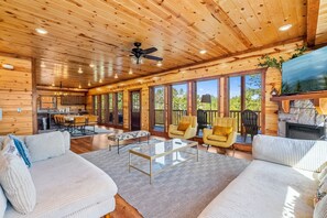 Une cabane en bois spacieuse, dotée d’un coin repas, d’un canapé et d’une cheminée.