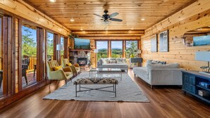 Eine geräumige Holzhütte mit großem Wohnbereich, Deckenventilator und Kamin.
