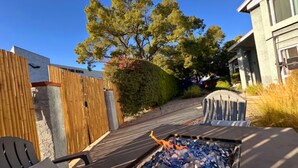 A patio area with outdoor seating, a fire pit, and a wooden fence. - Spacious 6-bedroom Dorm Room lodge with AC in charming Los Angeles (Los Angeles)
