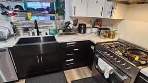 A modern kitchen with black cabinets, a stainless steel stove, and a sink. - Spacious 6-bedroom Dorm Room lodge with AC in charming Los Angeles (Los Angeles)