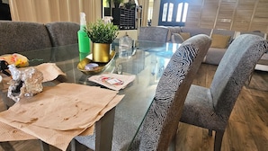 A dining area with a glass table, patterned chairs, a potted plant, and a decorative mirror. - Spacious 6-bedroom Dorm Room lodge with AC in charming Los Angeles (Los Angeles)