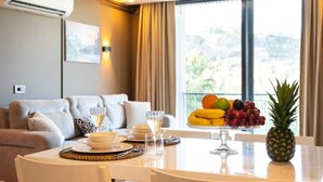 Un coin repas avec une table mise pour deux, un panier de fruits et un ananas posé sur la table.