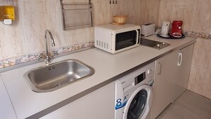 A compact kitchen with a sink, microwave, toaster, and a washing machine. - Nest Style Navas (Granada)