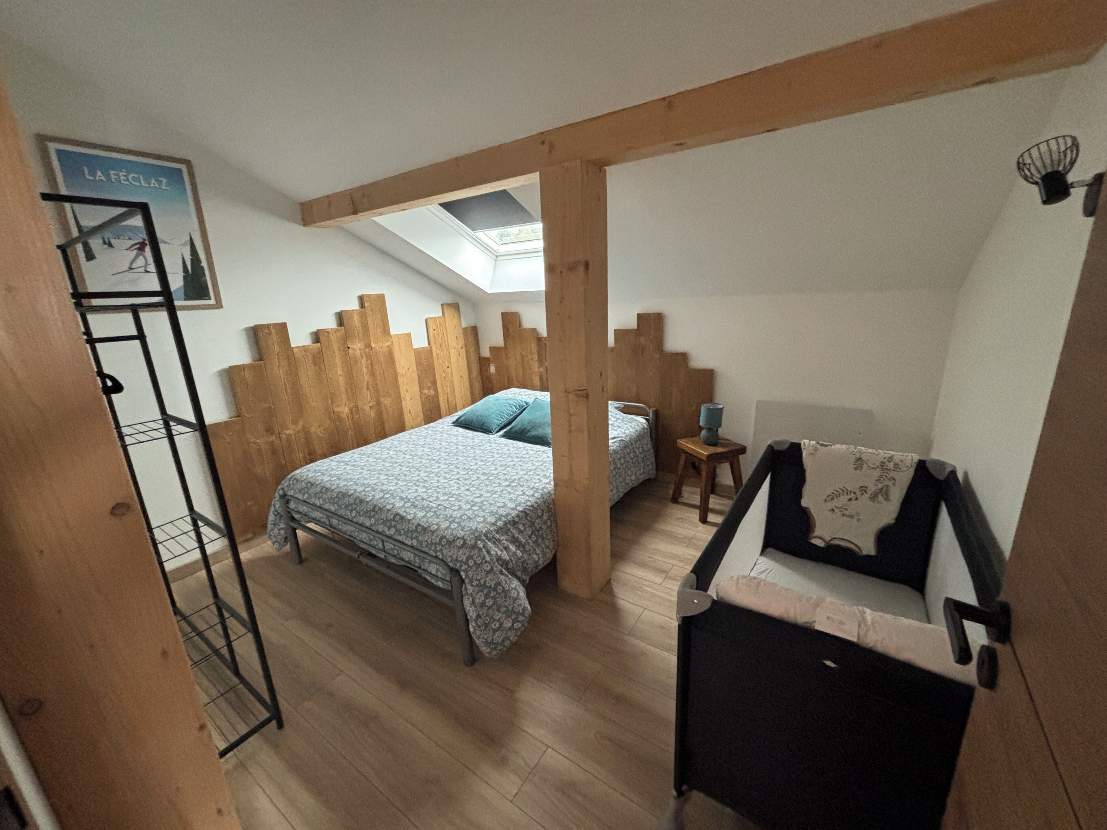 Une chambre à coucher comprenant un lit, un petit lit, une chaise, une étagère et une lucarne.