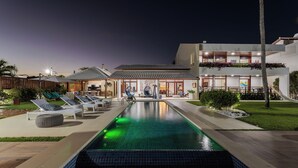 A pool area with lounge chairs, a building with a tiled roof, and a well-lit entrance. - Casa Manaua: beachfront property with incredible views in Barra de São Miguel (Barra de São Miguel)