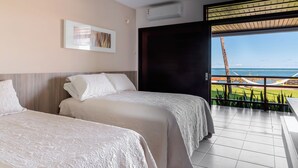 A hotel room with two beds, a large window with a view of the ocean, and an air conditioning unit. - Casa Manaua: beachfront property with incredible views in Barra de São Miguel (Barra de São Miguel)