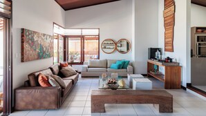A modern living room with a sofa, coffee table, and a wooden cabinet. - Casa Manaua: beachfront property with incredible views in Barra de São Miguel (Barra de São Miguel)