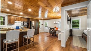Una cocina amplia con armarios de madera, un comedor con sillas y vistas a través de una puerta.