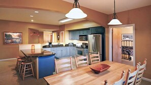 Una cocina moderna con armarios azules, una isla central y un comedor con mesa y sillas de madera.
