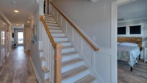 Eine Treppe mit Holzwandleisten führt zu einem Schlafzimmer mit Bett und Kopfteil.
