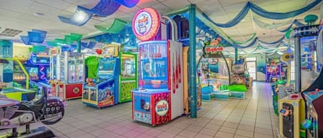 Un salón de juegos interior con diversas máquinas recreativas, incluyendo un destacado juego llamado '300'.
