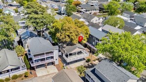 Un barrio residencial con varias casas de dos pisos, un monumento rojo en el centro y abundante vegetación circundante.