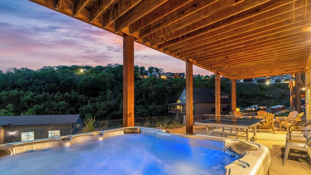 Un jacuzzi bajo una pérgola de madera con vistas a una zona residencial y árboles.