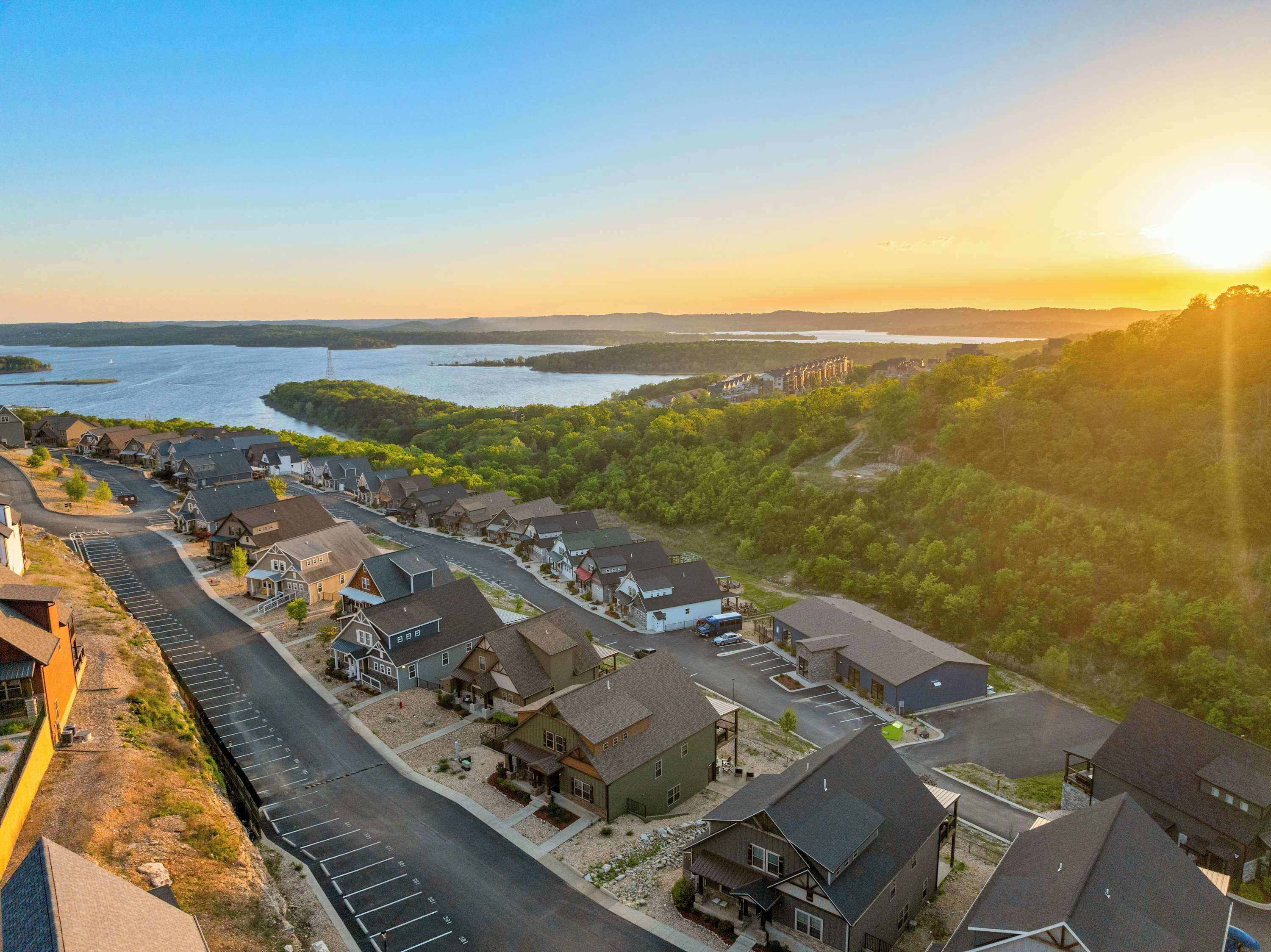 A residential area with houses, a parking lot, and a body of water in the background.