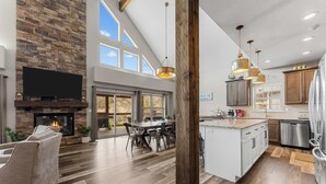 Amplia sala de estar con chimenea, mesa de comedor y cocina equipada con electrodomésticos modernos.