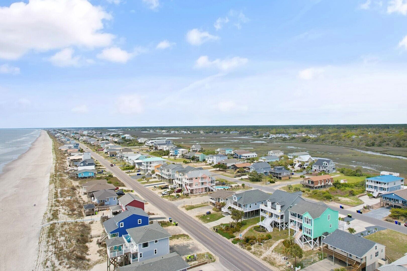 Una zona residencial costera con casas, una playa y una carretera.