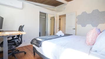Une chambre à coucher avec un lit, un bureau, une chaise et une armoire.