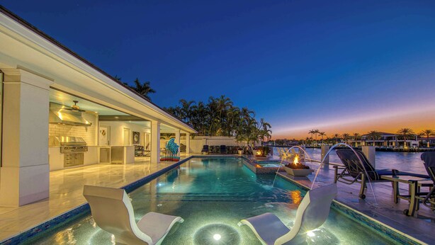Uma piscina com espreguiçadeiras, um bar e vista para a água.
