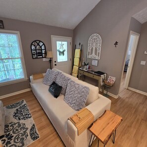 Un salon comprenant un canapé, une table basse en bois, un tapis à motifs, une porte avec un vitrage dépoli et un élément décoratif mural.