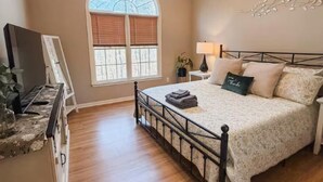 Ein Schlafzimmer mit Bett, Fernseher, Fenster und Wanddekoration.