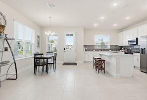 A modern kitchen with white cabinets, a central island, and a modern appliances. - Lux 4 bed Mins! To HCA & Advent & Gemini Springs (DeBary)