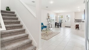 Amplia sala de estar con escalera, una mesa de comedor y una zona de cocina.