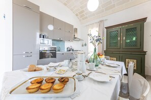 Un'area pranzo con un tavolo apparecchiato per la colazione, con dolci e tè.