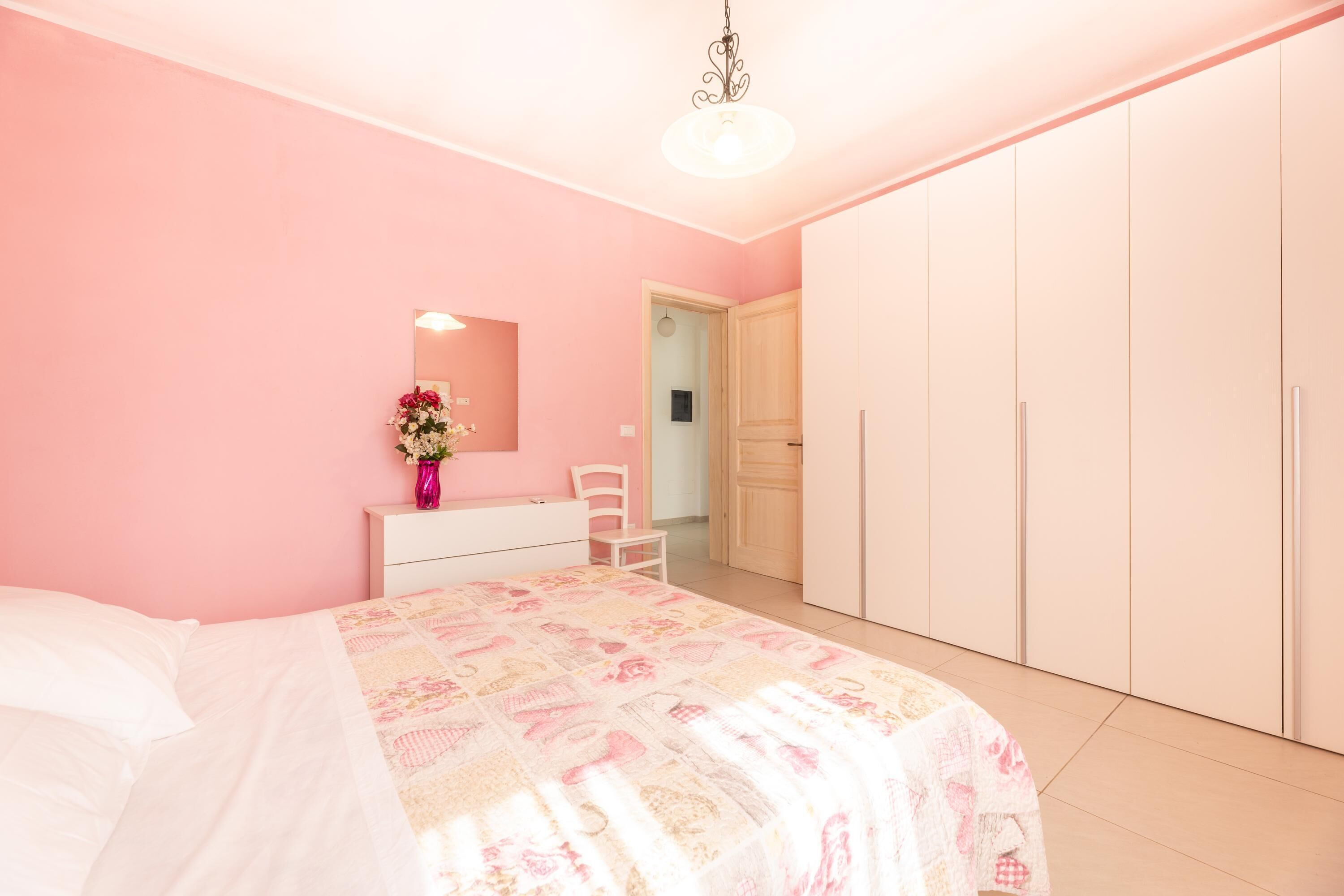 Een slaapkamer met een bed, dressoir, spiegel en kledingkast.