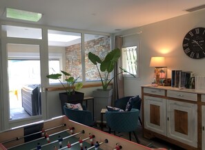 Een kamer met een tafelvoetbaltafel, een klok, een boekenkast en een raam met uitzicht.