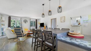 Ein modernes Wohnzimmer mit Essbereich, einer Couch, einem Fernseher und einem Bücherregal.