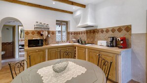 A kitchen with wooden cabinets, a microwave, a toaster, and a coffee maker. - Holiday Home 'Missia' with Mountain View, Wi-Fi and Air Conditioning (Porto-Vecchio)