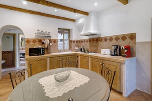 A kitchen with wooden cabinets, a microwave, a toaster, and a coffee maker. - Holiday Home 'Missia' with Mountain View, Wi-Fi and Air Conditioning (Porto-Vecchio)