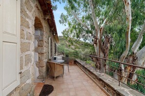 A stone building with a balcony, outdoor seating, and a view of trees and hills. - Holiday Home 'Missia' with Mountain View, Wi-Fi and Air Conditioning (Porto-Vecchio)