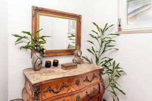 A wooden dresser with ornate carvings, a large mirror with a gold frame, and two potted plants. - Myhomereservation: chic vintage villa with terrace and barbecue (Parede)