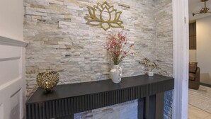 A stone wall with a decorative lotus symbol, a vase with pink flowers, and a golden spherical object on a dark console table. - The Inn at Dupont (Washington)