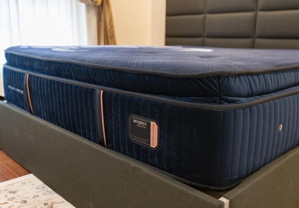 A bed with a dark blue mattress and a tag labeled 'RESERVE.'