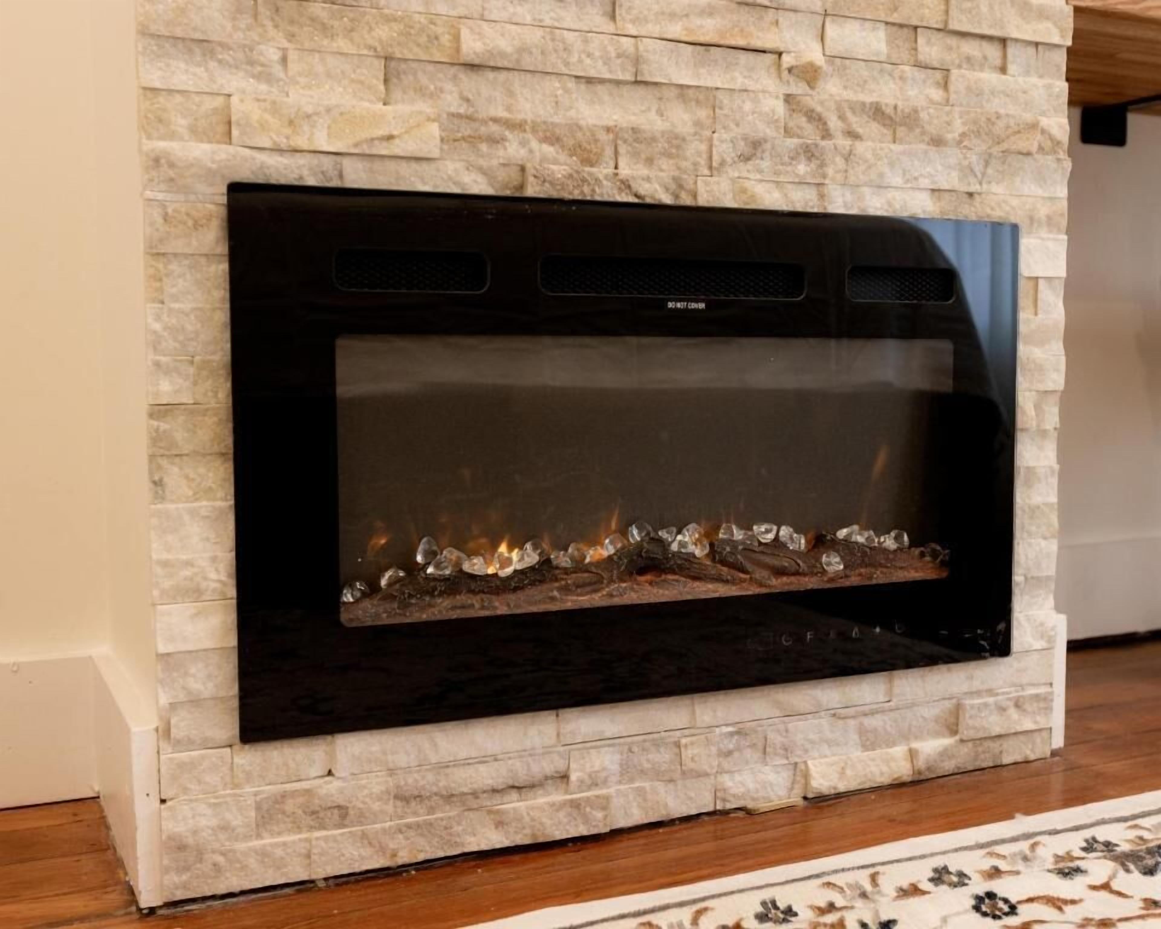 Una chimenea con fachada de piedra y frente de vidrio negro.