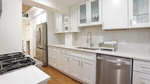 A modern kitchen with white cabinets, stainless steel appliances, and a marble countertop. - The Inn at Dupont (Washington)