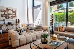 Un salon moderne avec un canapé, une table basse et une vitrine en verre contenant une plante.