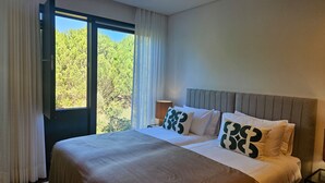Ein Hotelzimmer mit einem Bett, einem Nachttisch, einer Lampe und einem Fenster mit Vorhängen.