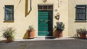 Un immeuble avec une porte verte, portant le numéro 10, des plantes en pot et des fenêtres grillagées.