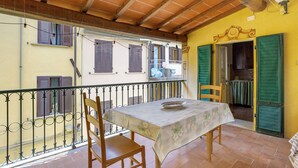Un balcon avec une table et des chaises, une balustrade et une vue sur les bâtiments voisins.