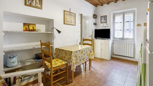 Une cuisine équipée d’une table à manger, de chaises, d’un téléviseur et d’une fenêtre.