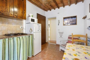 Una cocina con estufa, microondas, refrigerador y un armario de madera.