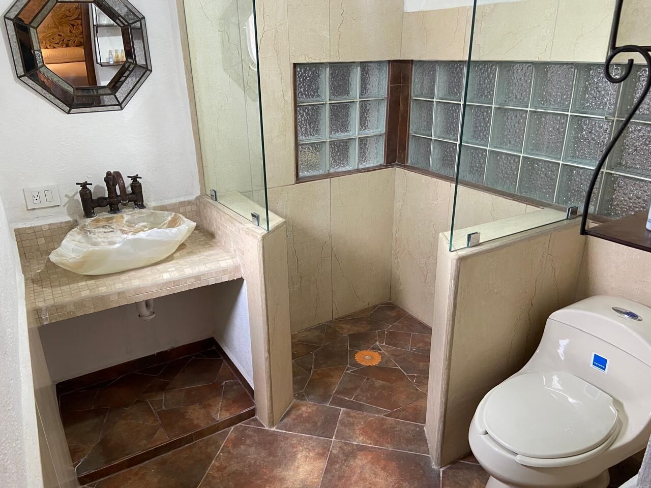 A bathroom with a sink, toilet, and a mirror.